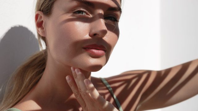 Young,Woman,With,Shadow,Of,Palm,Leaves,On,White,Wall.